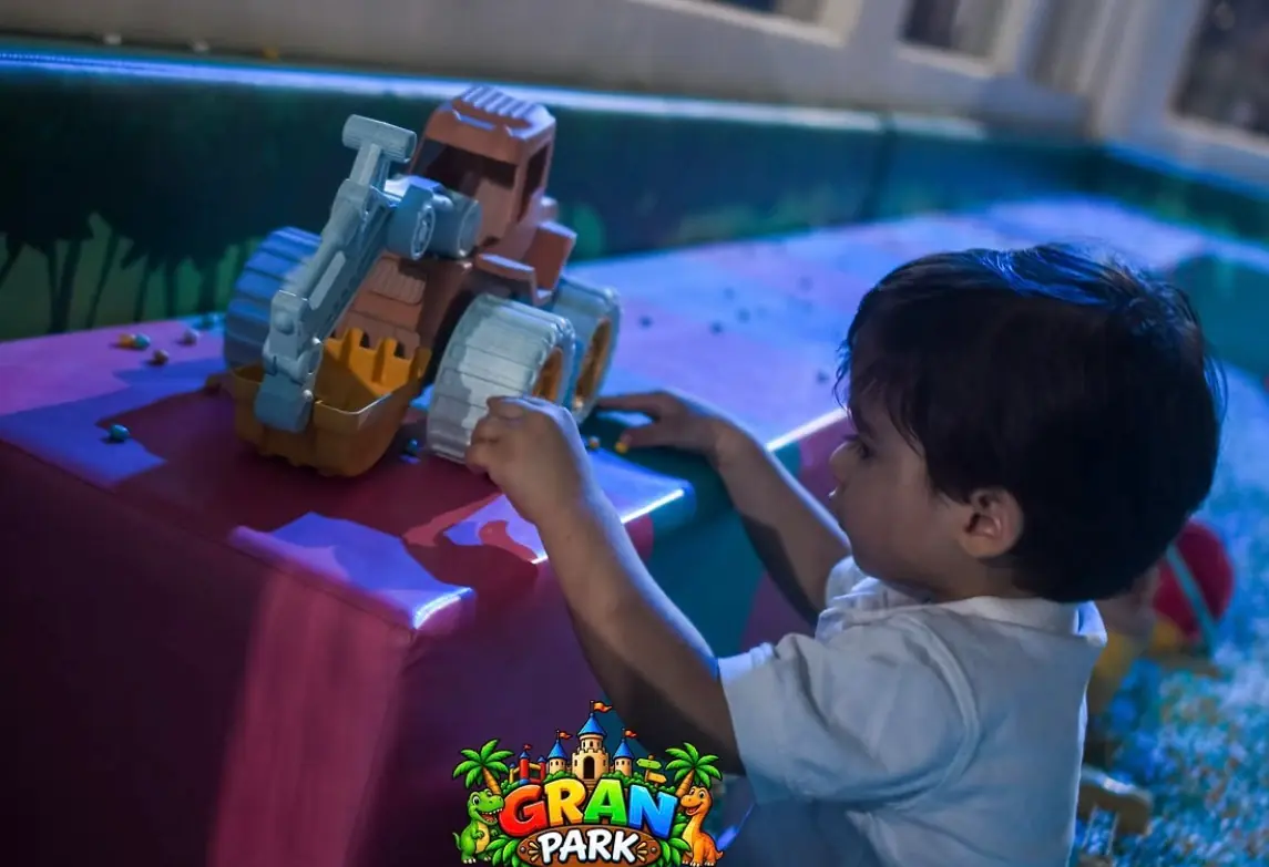 Niño jugando con una volqueta en el arenero de bolitas